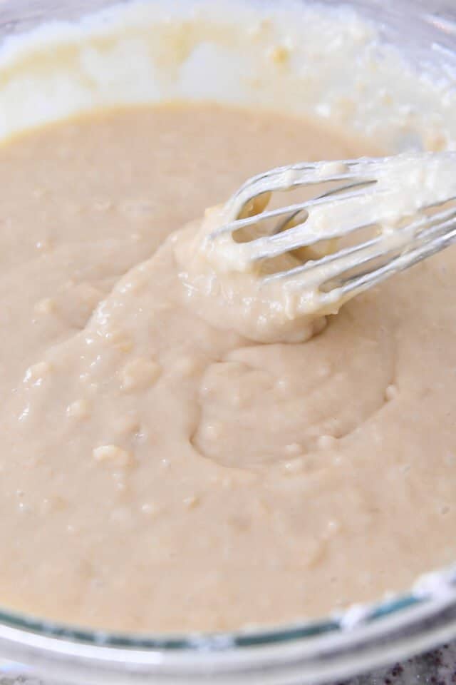 Banana bread batter getting mixed by a whisk. 