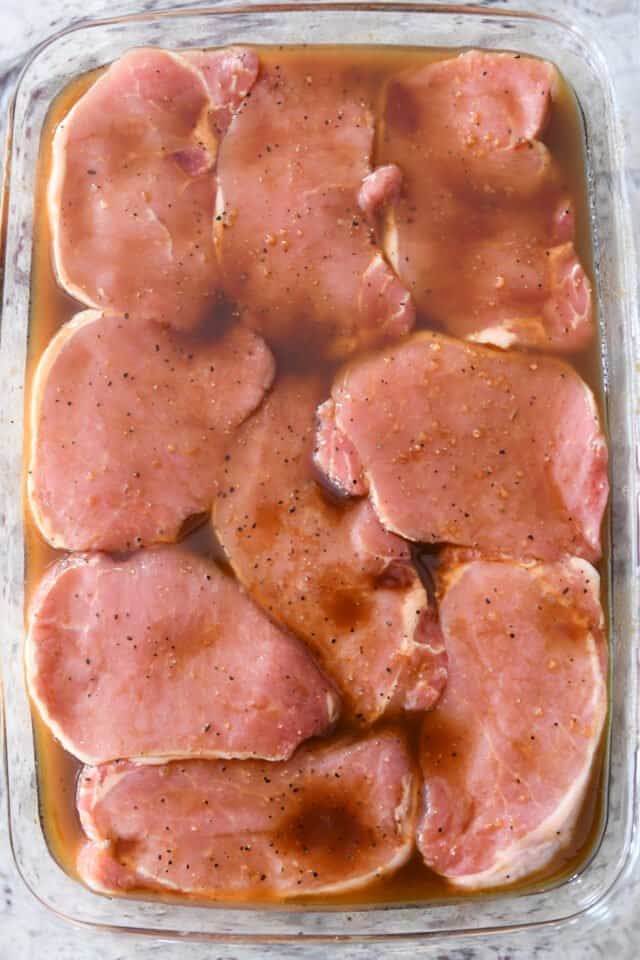 Glass pan with pork chops and marinade.