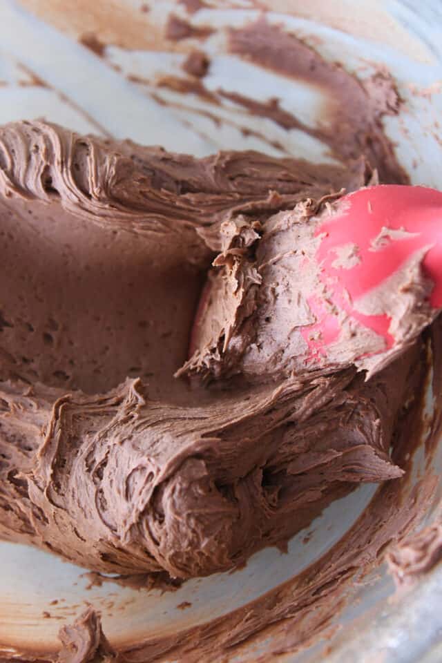 Pressing out air bubbles in frosting with red rubber spatula.