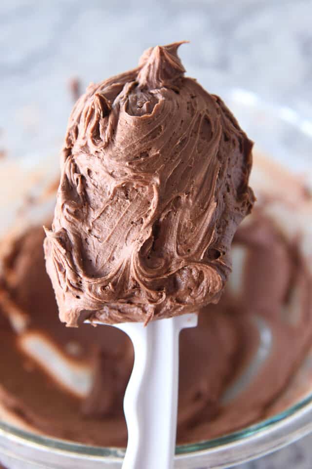 Swirly scoop of chocolate buttercream frosting on white spatula.