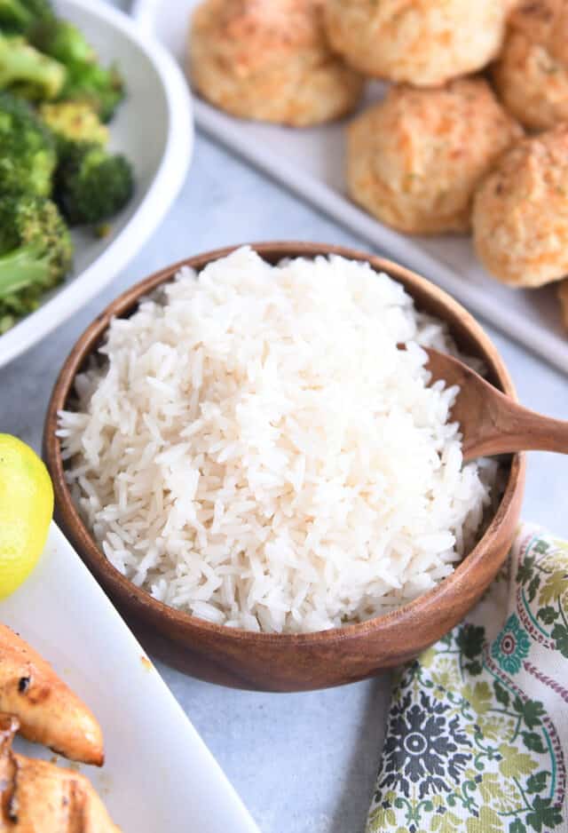 Coconut rice in wooden bowl with wooden spoon.
