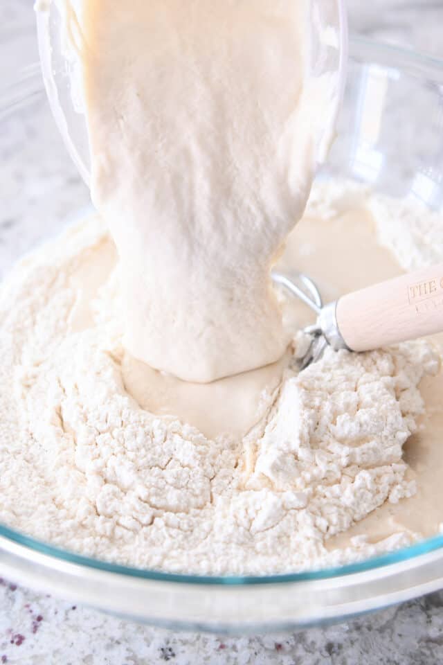 Pouring in sourdough discard to bowl with flour.