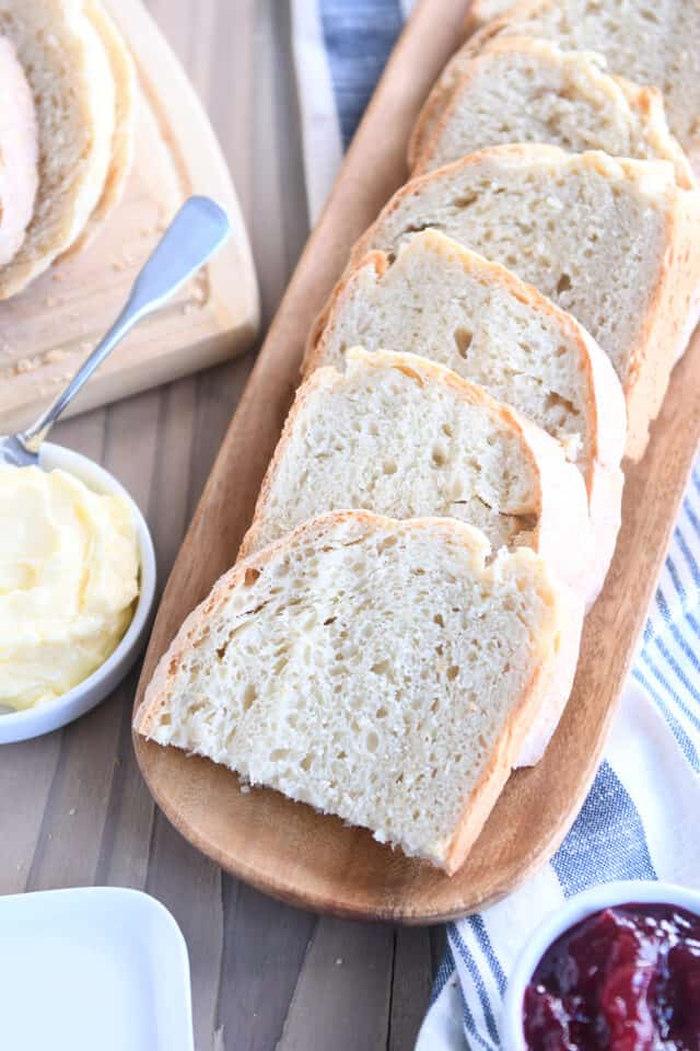 Six half slices of sourdough peasant bread on wooden tray.