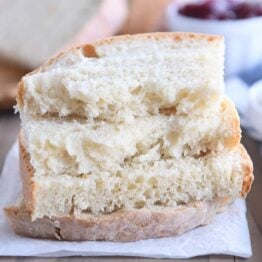 four half slices of baked sourdough peasant bread stacked on parchment paper