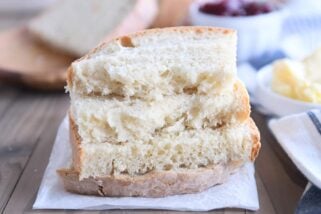 four half slices of baked sourdough peasant bread stacked on parchment paper