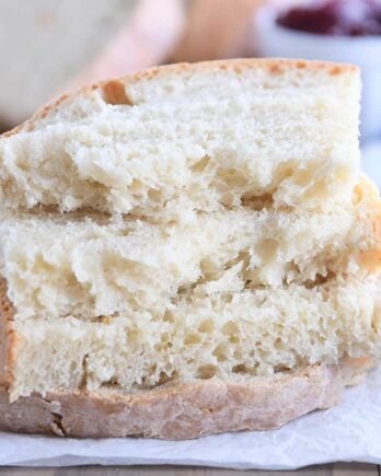 four half slices of baked sourdough peasant bread stacked on parchment paper