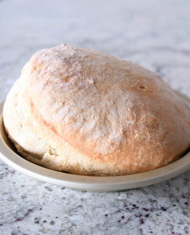 Baked loaf of sourdough peasant bread in metal tin.