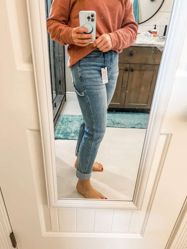 Woman in mirror with jeans and sweatshirt.