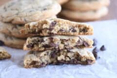 three half chocolate chip cookies stacked on each other on white parchment paper