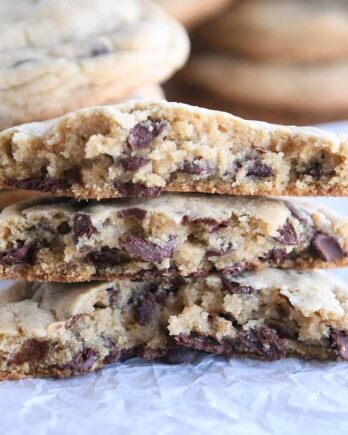 three half chocolate chip cookies stacked on each other on white parchment paper