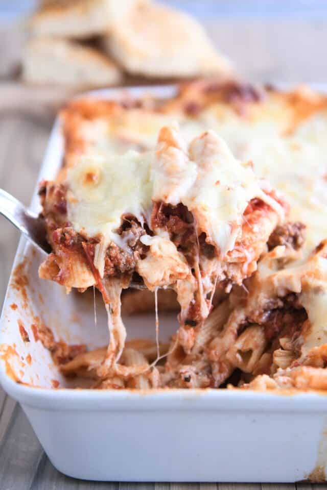 scooping serving of weeknight pasta bake out of white 9X13-inch pan