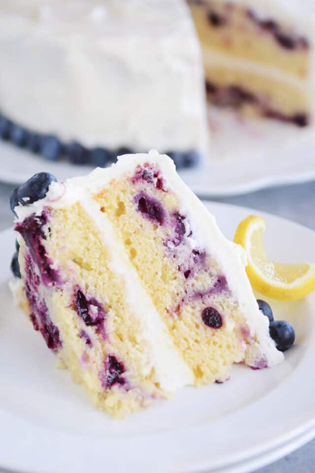 Double layer lemon blueberry cake on white plate.