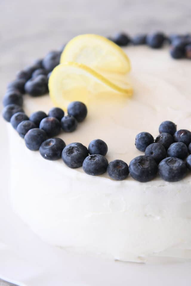 Frosted lemon blueberry cake with blueberries around the top.