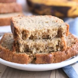 two halves of banana bread on top of full slice on white plate