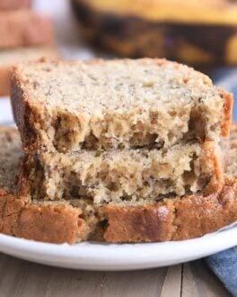 two halves of banana bread on top of full slice on white plate