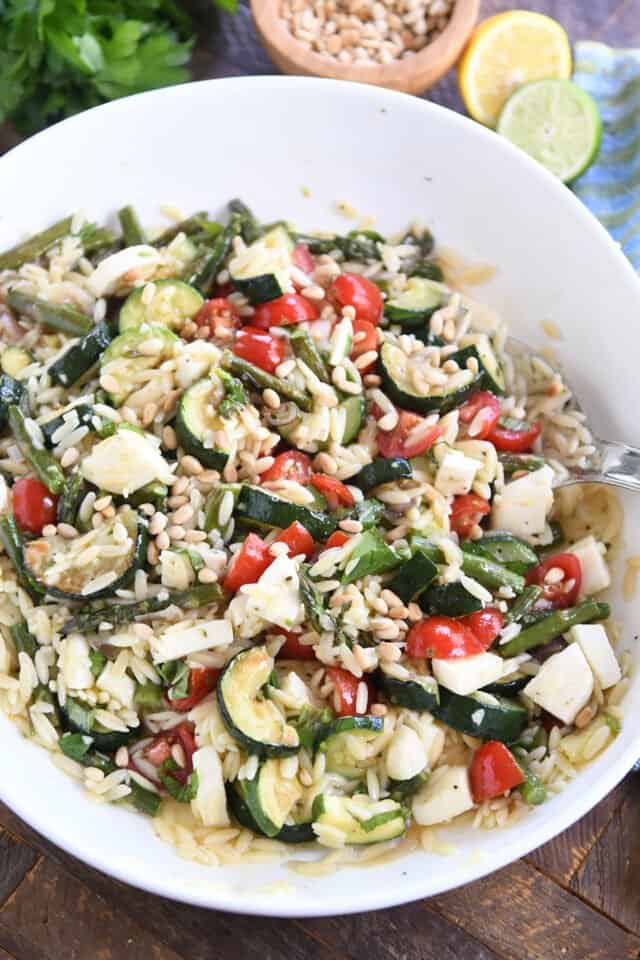 white bowl with lemon orzo salad, tomatoes, roasted asparagus and fresh mozzarella