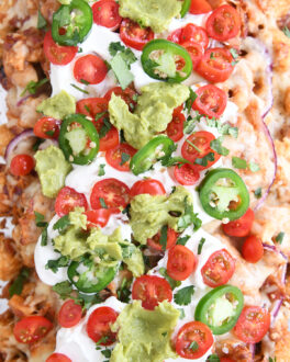 close up top down view of bbq chicken totchos with sour cream, tomatoes and guacamole