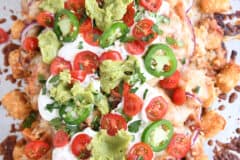 close up top down view of bbq chicken totchos with sour cream, tomatoes and guacamole
