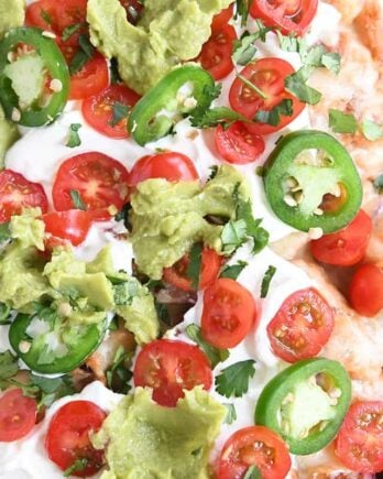 close up top down view of bbq chicken totchos with sour cream, tomatoes and guacamole