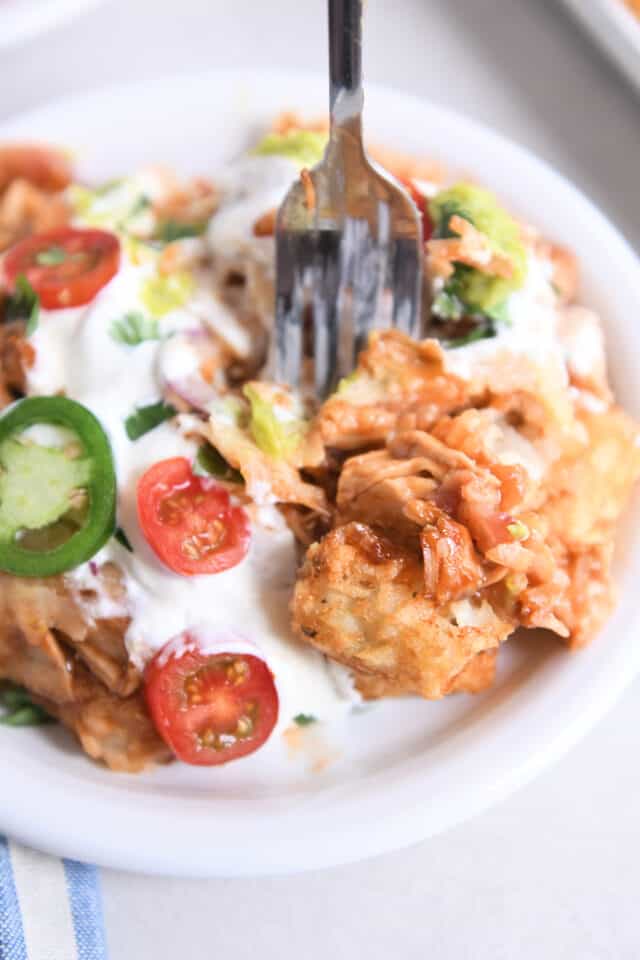 Fork digging into plate of bbq chicken totchos.