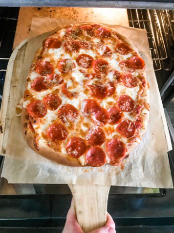 Pizza fatta in casa su pala di pizza in legno.