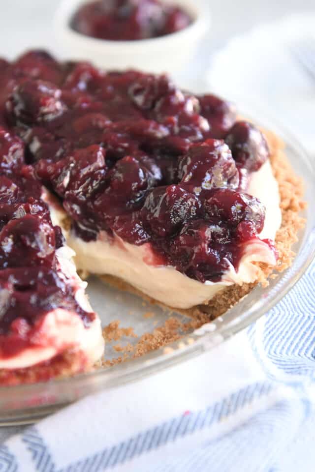 Cherry cheesecake pie in glass pie plate with slice cut out.