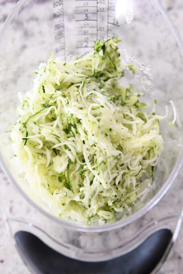 Liquid measuring cup filled to the two cup line with shredded zucchini.