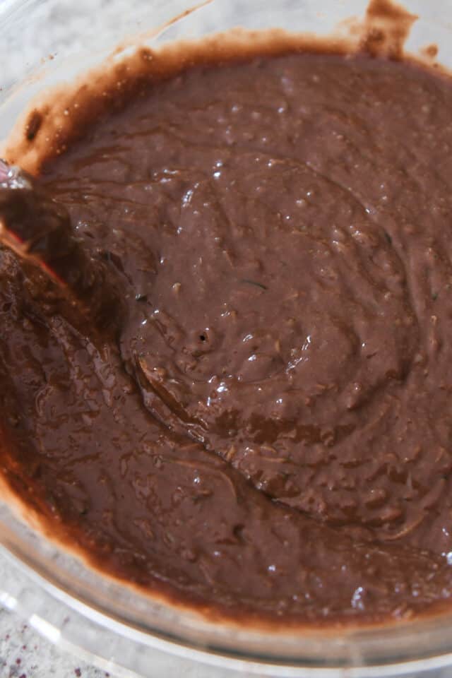 Stirring chocolate zucchini cake batter with rubber spatula.