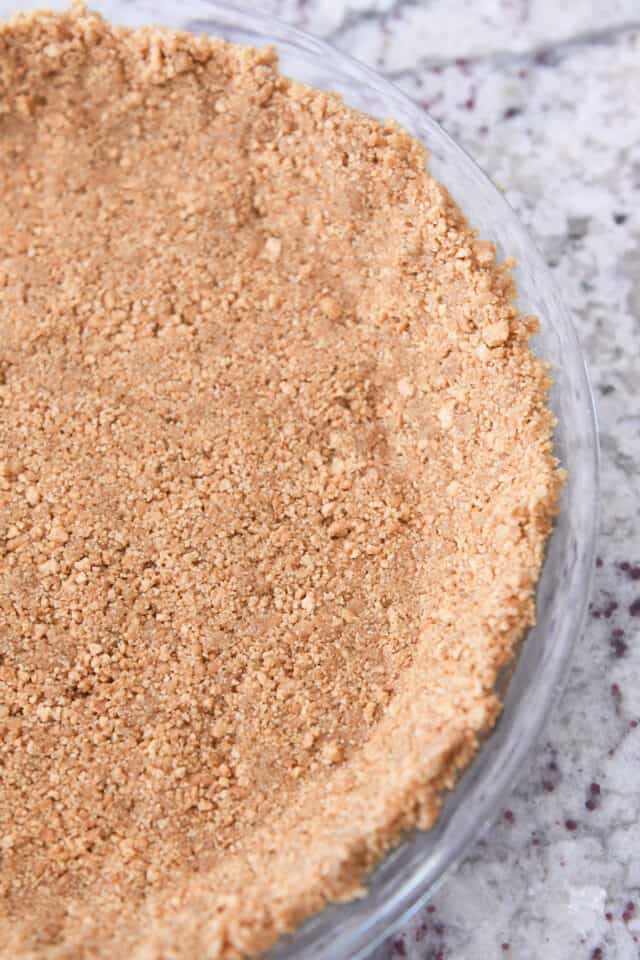 Half view of graham cracker crust in pie plate.