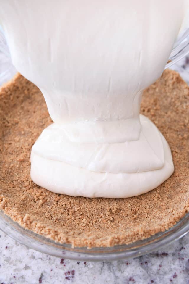 Pouring cheesecake batter into graham cracker crust.