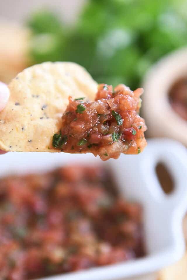 holding tortilla chip dipped in quick and easy homemade salsa