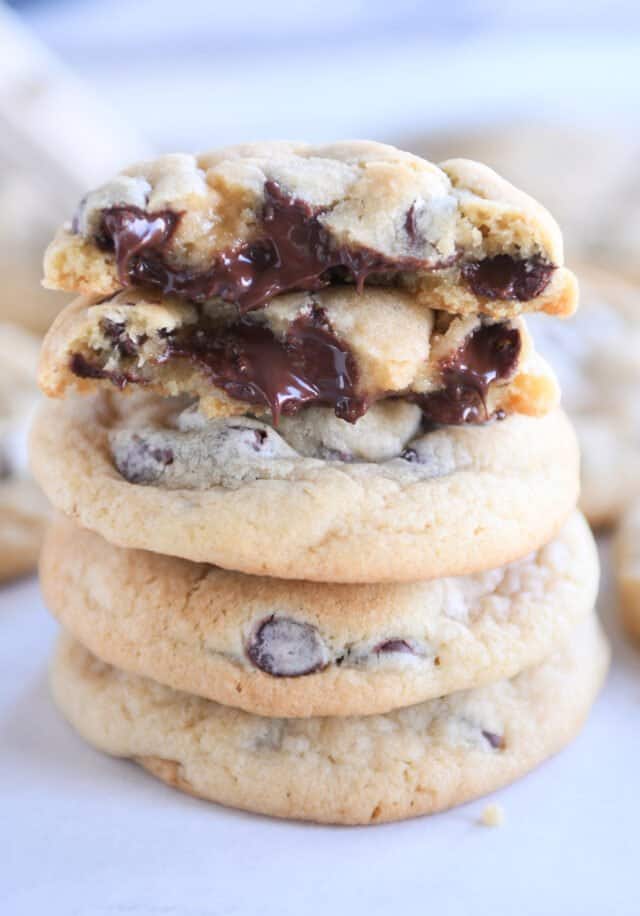 Stack of three soft chocolate chip cookies with two half cookies on top.