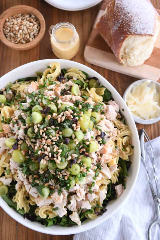 Large white bowl with ingredients for vineyard chicken and pasta salad.