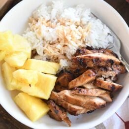 top down view of grilled teriyaki chicken in white bowl with rice and pineapple