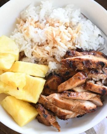 top down view of grilled teriyaki chicken in white bowl with rice and pineapple