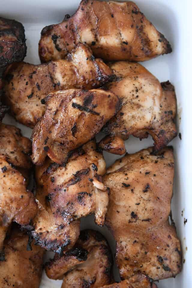 Grilled teriyaki chicken thighs in white dish.