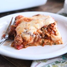 serving of cheesy zucchini spaghetti casserole on white plate with fork