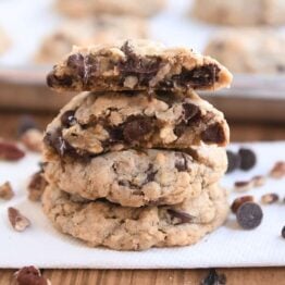 Two cowboy cookies stacked with one cookie broken in half on top.