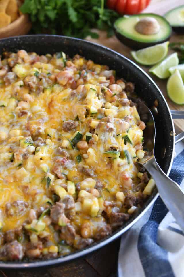 12-inch skillet with zucchini, ground beef, beans and seasonings covered in cheese.