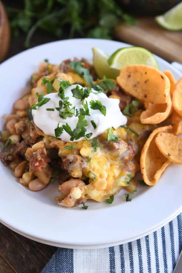 Cheesy tex-mex zucchini skillet with corn chips on white plate.