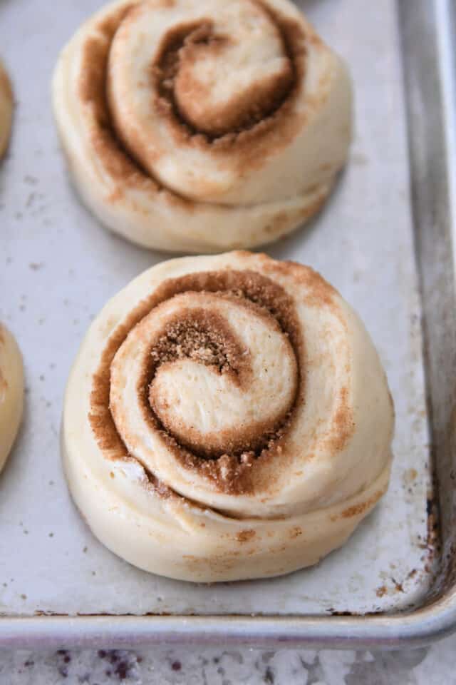 Unbaked cinnamon roll risen on sheet pan.