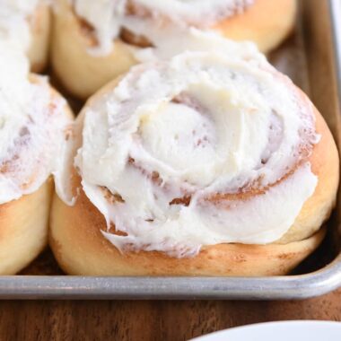 baked cinnamon rolls with frosting on sheet pan