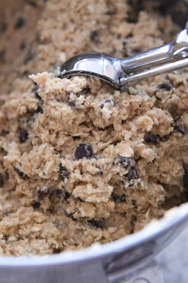 Cookie scoop digging into bowl of oatmeal chocolate chip cookie dough.