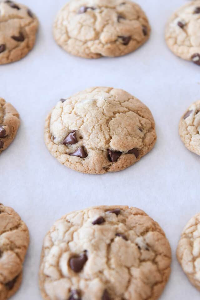 Baked chocolate chip cookies on parchment paper.