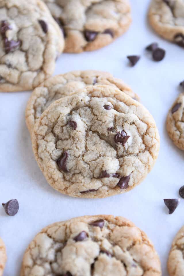 Two baked chocolate chip cookies on parchment paper.