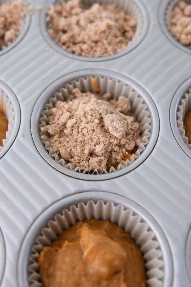Muffin batter in muffin liner with streusel on top.