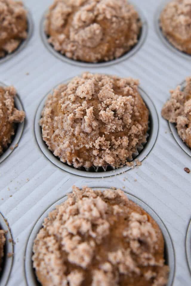 Baked pumpkin muffins in muffin tin with streusel topping.