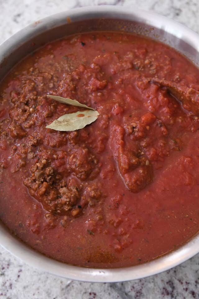 Pot with spaghetti sauce and two bay leaves.