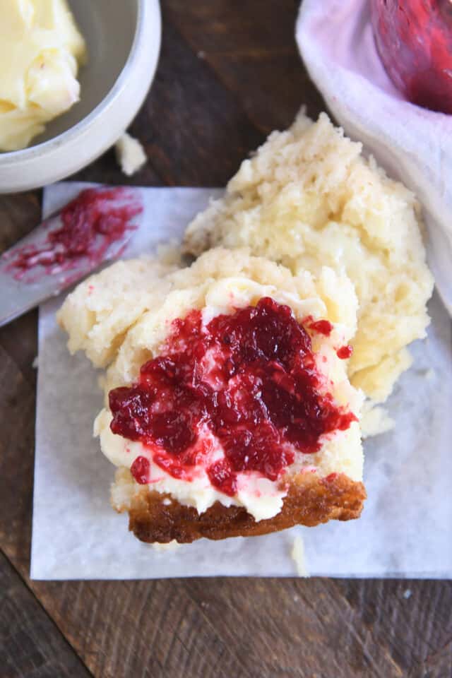 Butter and raspberry jam on half of a swim biscuit.