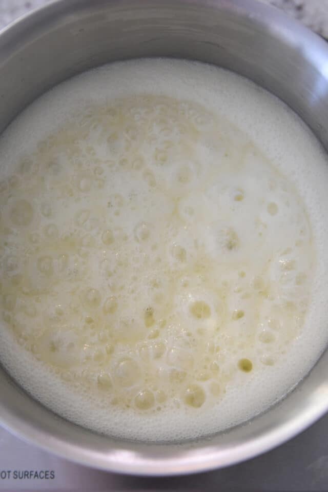 Cream colored syrup bubbling in saucepan.